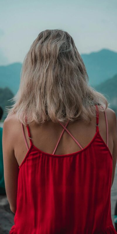 Three people meditate by the Ganges River in Rishikesh, India, with a serene mountain backdrop.